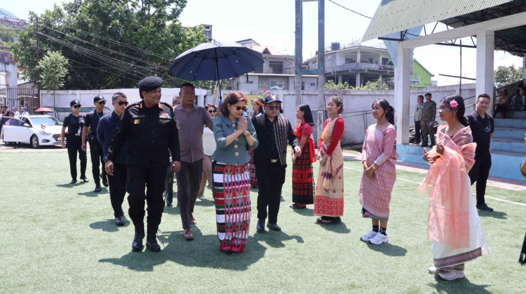 Minister Pi Lalrinpuii walking with senior police officers and women in traditional Mizo dress across the ground.