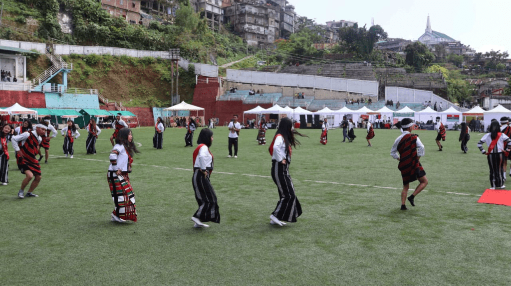 Female NCC cadets performing traditional Mizo dance on the green field.