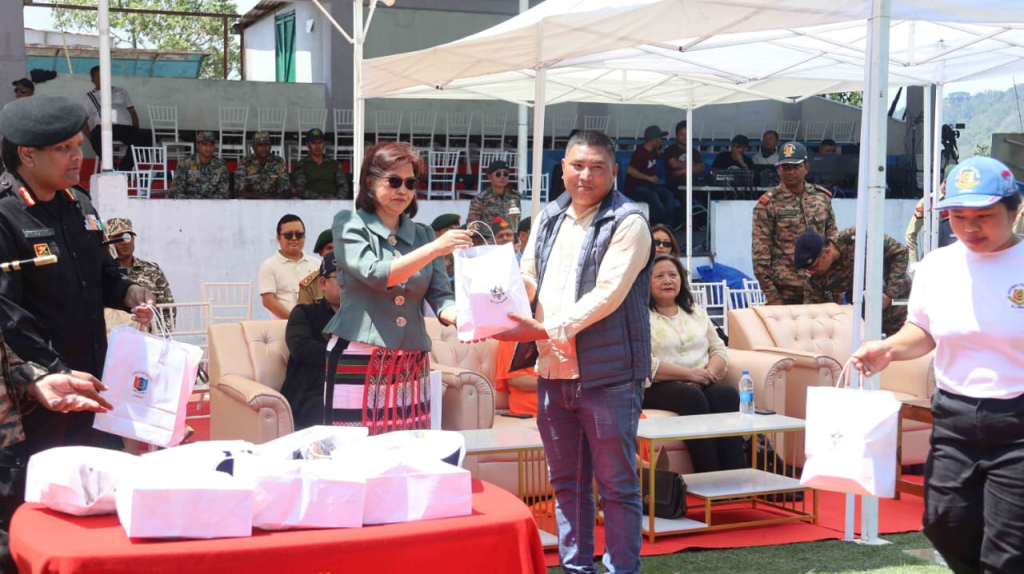 Minister Pi Lalrinpuii giving a gift to a civilian dignitary seated on stage.